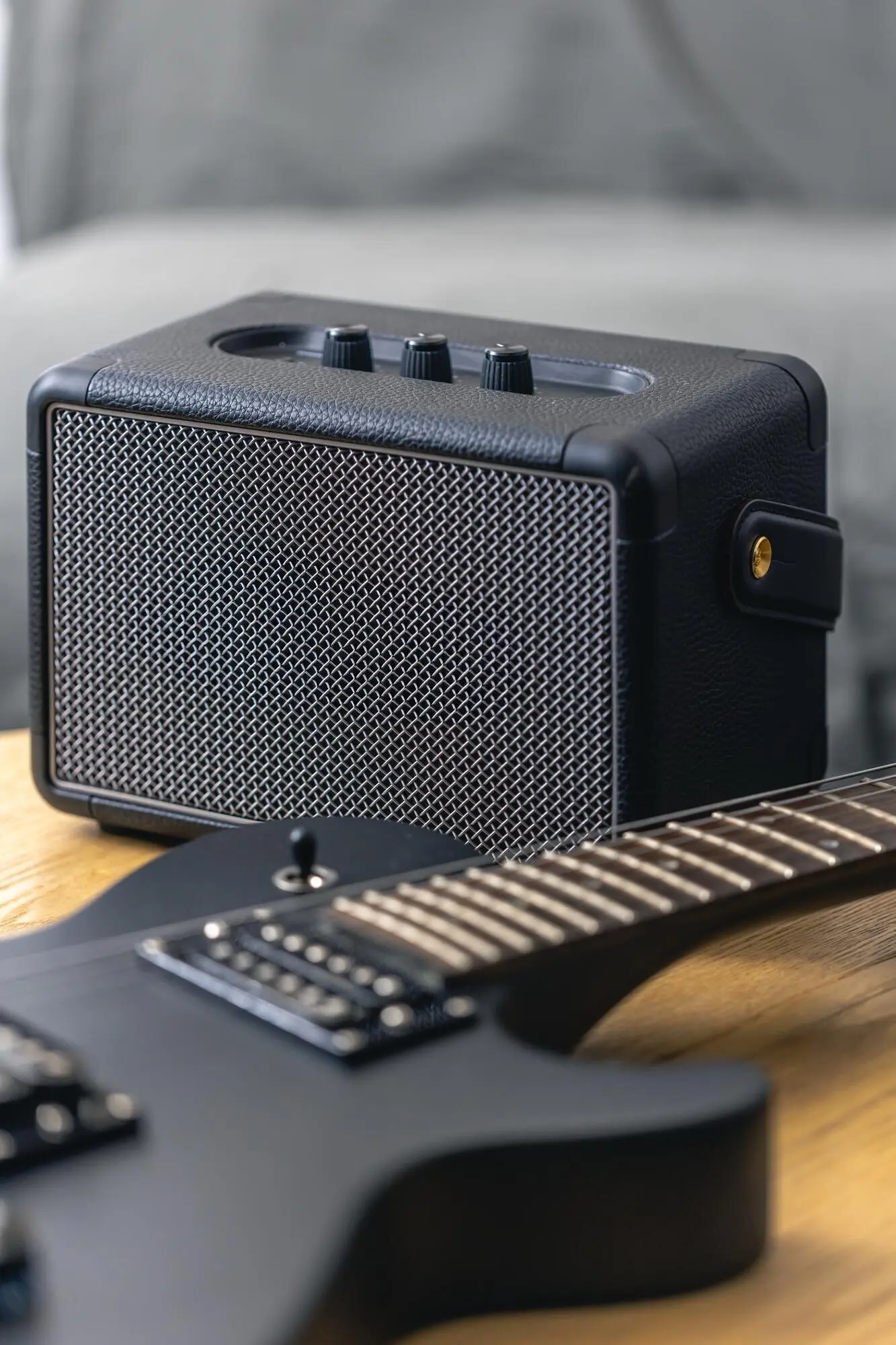 Close-up of musical equipment: a black electric guitar and a guitar amplifier speaker.